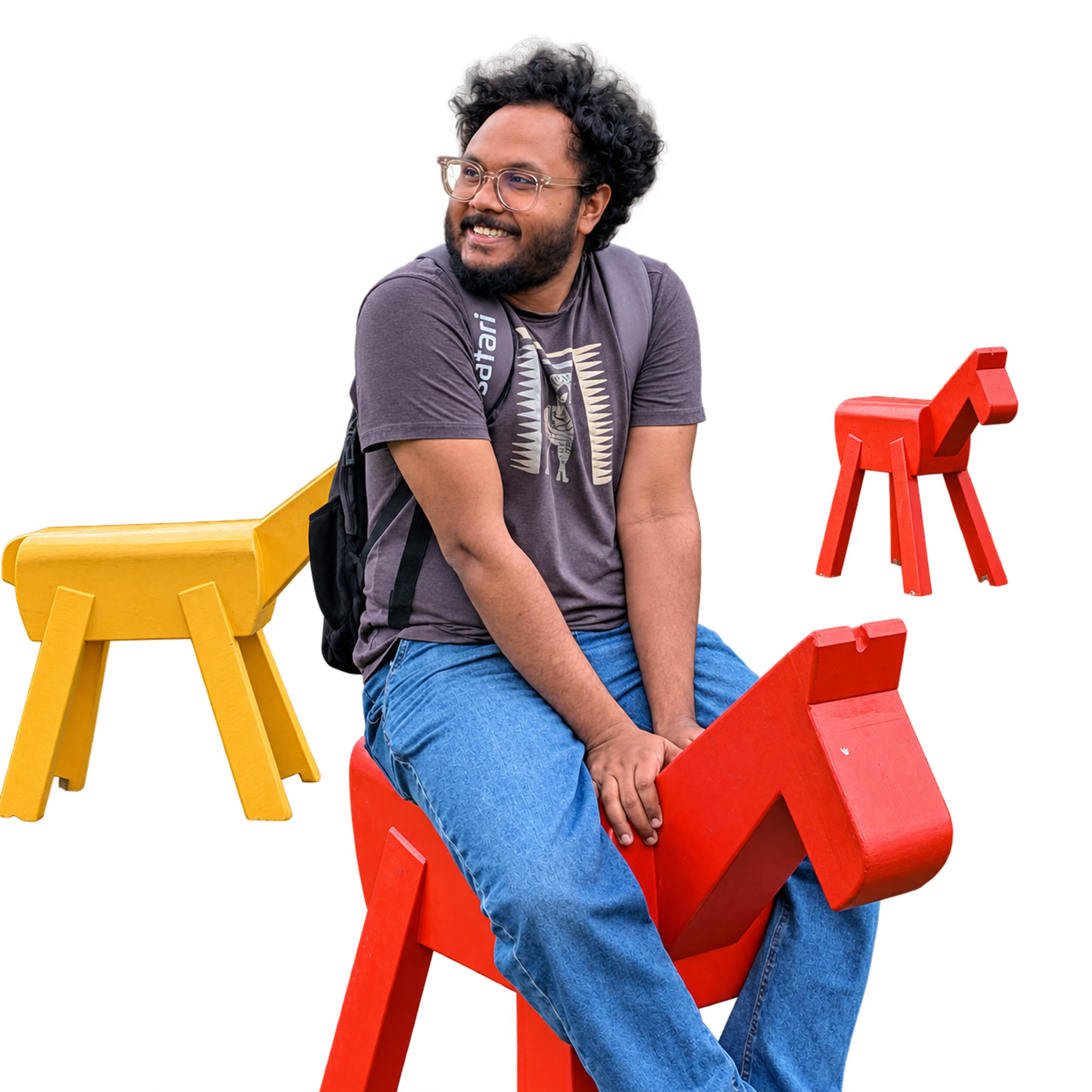 Dhruba smiling outdoors, seated on a red wooden horse.